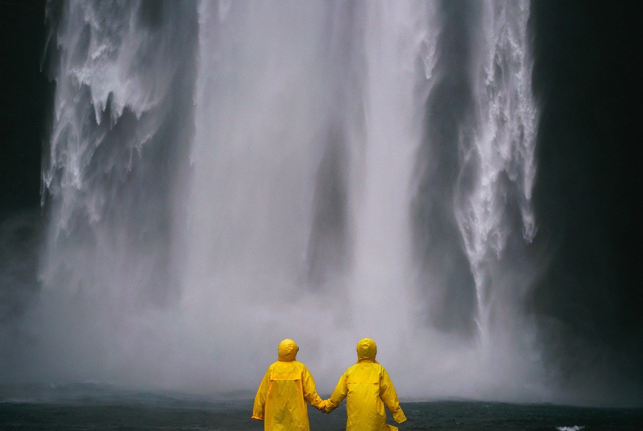 A couple watching a waterfall, holding hands